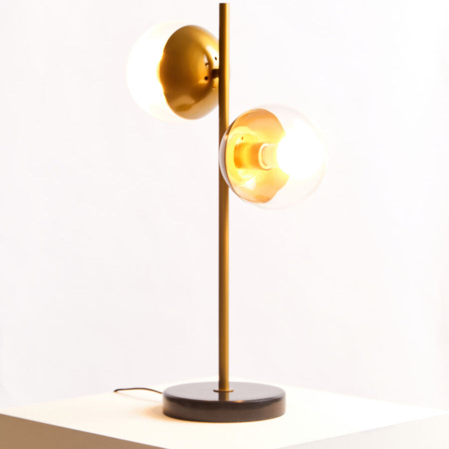 Modern table lamp with gold finish and black base on a white surface