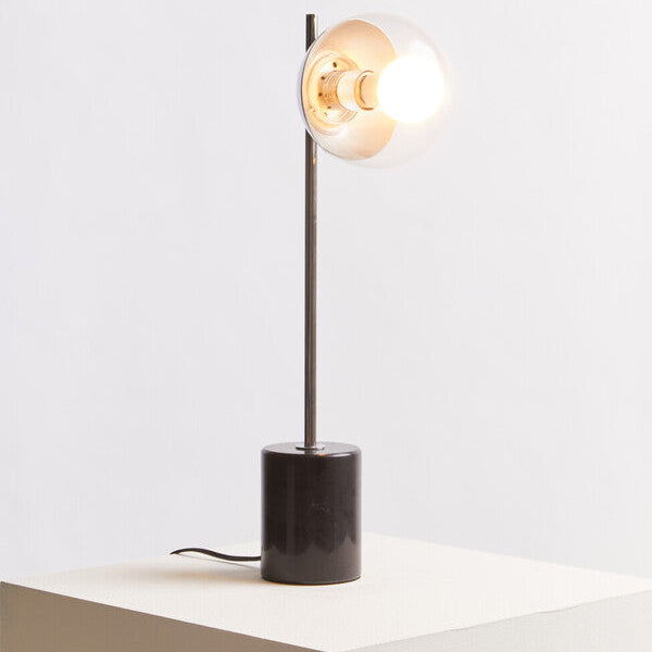 Modern table lamp with a black base and glass shade on a white surface.