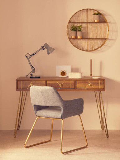Wooden desk with gray chair and lamp against a beige wall