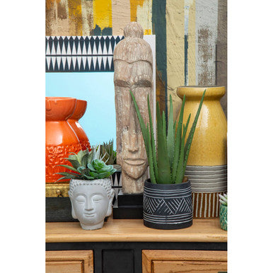 Decorative items including potted plants, vases, and a statue on a wooden surface with a colorful abstract painting in the background.
