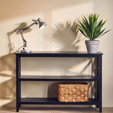 Navy console table with a lamp, plant, and basket against a beige wall.