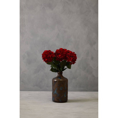Small brown vase with red flowers against a gray background