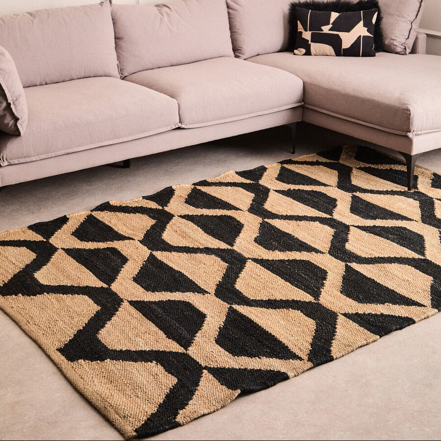 Geometric patterned rug in front of a light gray sectional sofa.