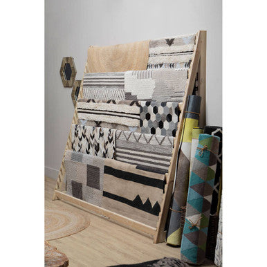 Wooden rack displaying various patterned rugs on a light wooden floor.