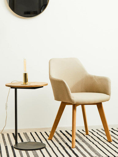 Beige chair and small round table with a candle in a minimalistic room.