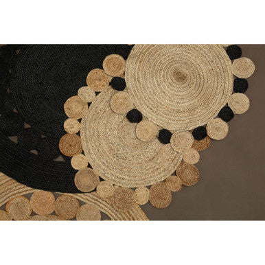 Round woven mat with circular patterns and black pom-poms on a brown background