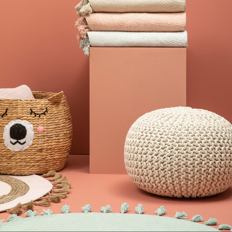Stack of folded towels on a pink pedestal against a peach wall with decorative elements.