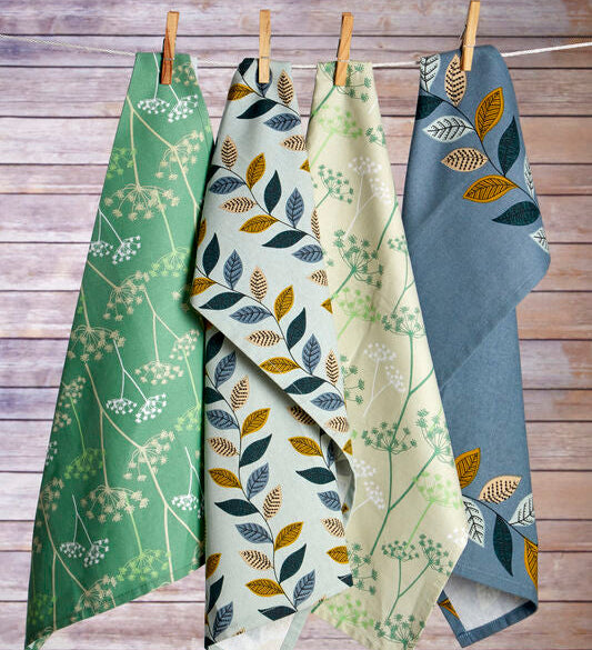 Four green and blue patterned towels hanging on a clothesline against a wooden background.