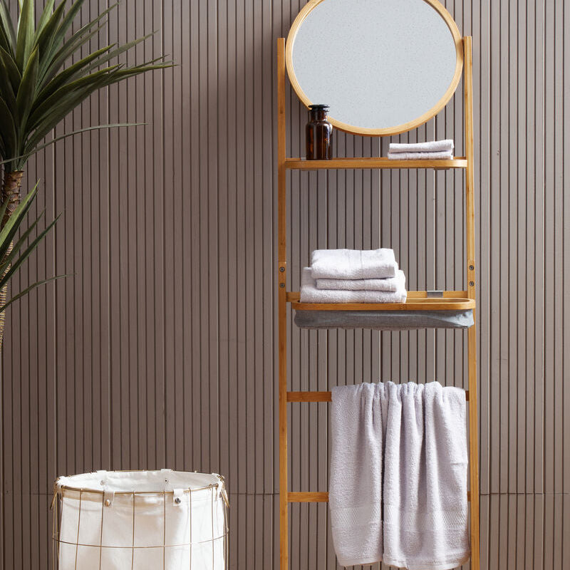 Bathroom shelf with mirror, towels, and laundry basket against a striped wall.