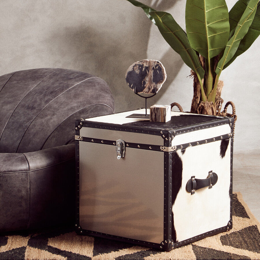 Vintage-style trunk used as a side table with a plant and mirror in a living room setting.