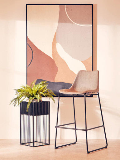 Modern bar stool with a plant and abstract wall art in a minimalistic setting