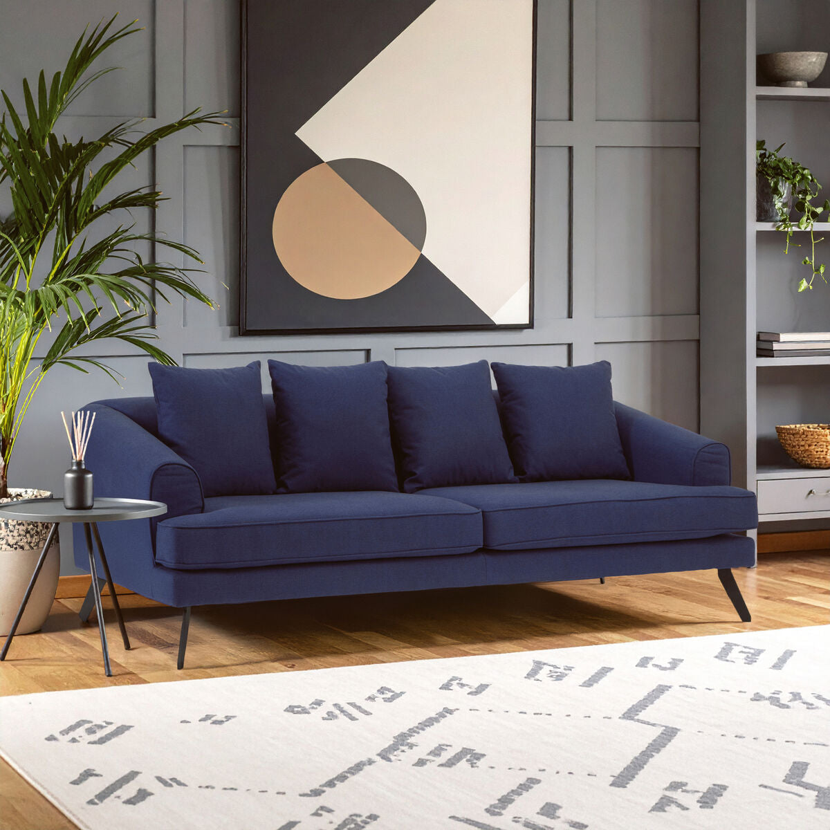 Blue sofa in a living room with a geometric art piece on the wall.