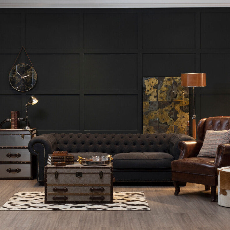 Modern living room with dark walls, leather sofa, and armchair.
