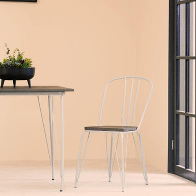 White chair next to a small table with a plant on a beige wall.