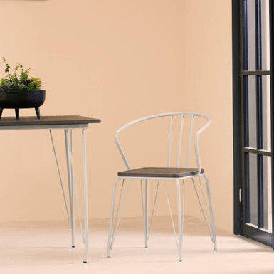 Modern chair and table set against a beige wall with a plant on the table.