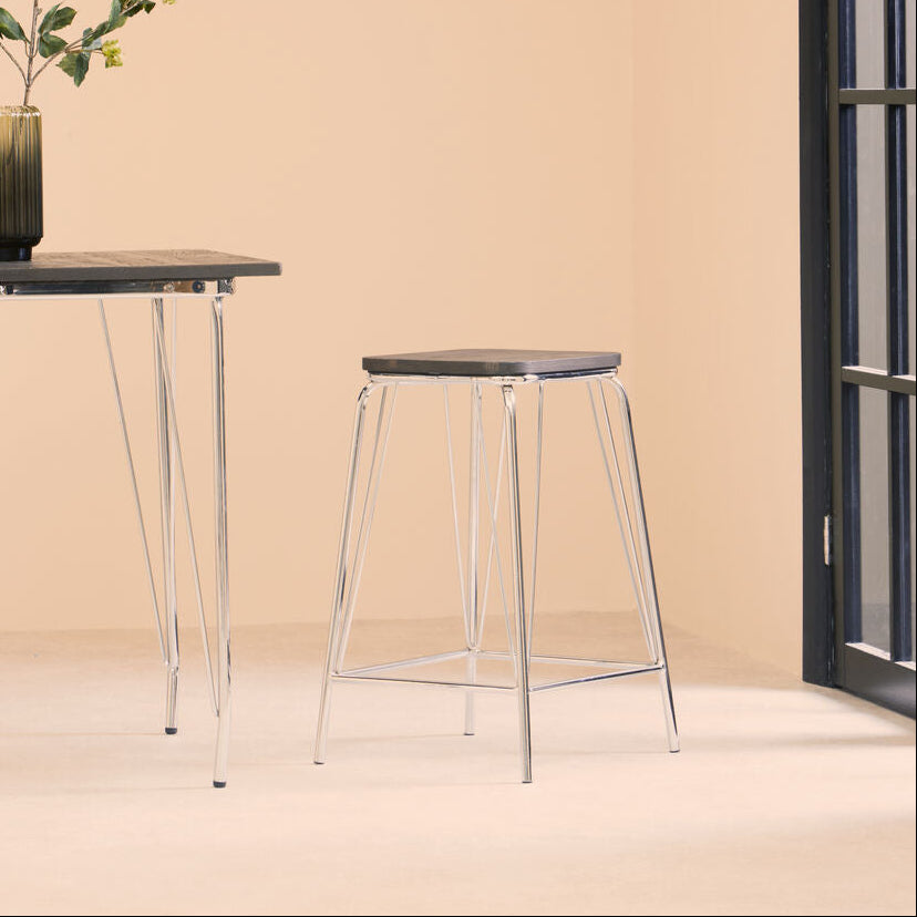 Modern stool and table set against a beige wall with a decorative plant.