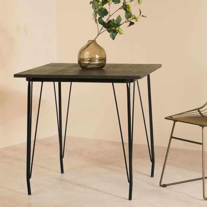 Small table with a vase and plant next to a chair on a beige background