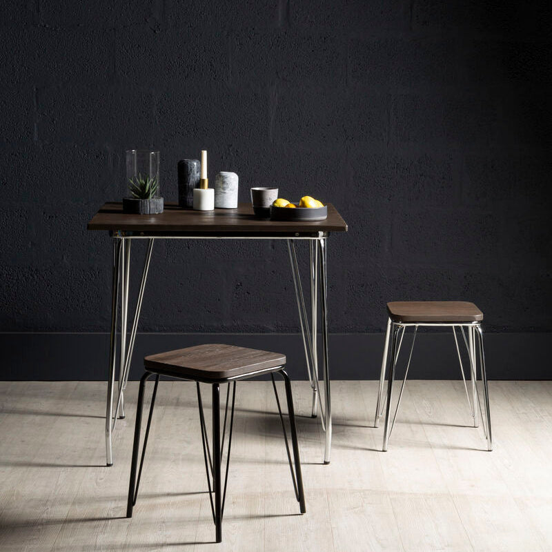 Dining table with two stools against a dark wall