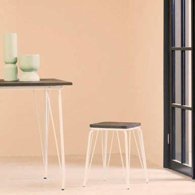 Minimalist interior with a table and stools against a peach wall.
