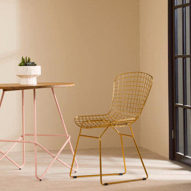 Modern wire chair and table in a minimalistic room with a neutral color palette.