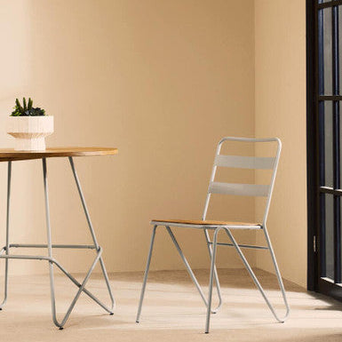 Modern chair and table set against a beige wall with a plant on the table.