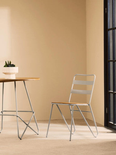 Modern chair and table set against a beige wall with a plant on the table.