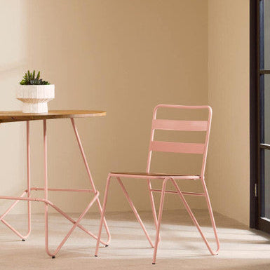 Pink metal chair and table against a beige wall