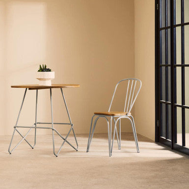 Modern chair and table set against a beige wall with a black-framed window.