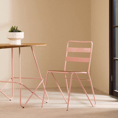 Pink metal chair and table against a beige wall