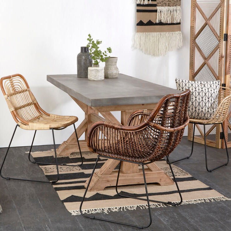 Dining area with a wooden table and wicker chairs on a patterned rug.