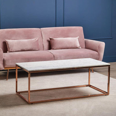 Pink sofa with a coffee table against a blue wall