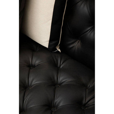 Close-up of a black leather sofa with tufted backrest