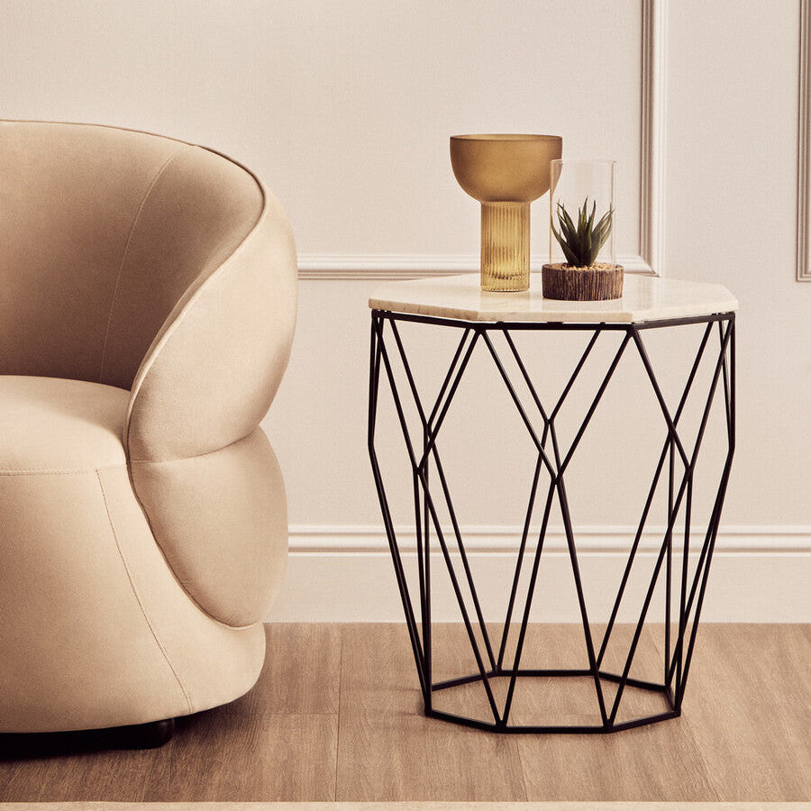 Modern interior with a beige armchair and a black wire side table.
