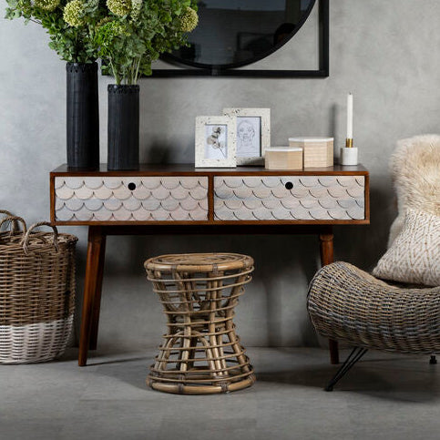 Living room with wicker chair, side table, and decorative items against a gray wall.