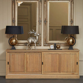Wooden sideboard with two large mirrors above it, flanked by two lamps.