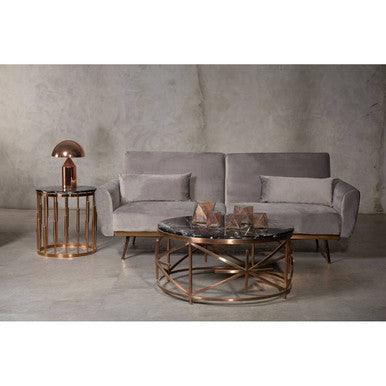 Gray sofa with bronze coffee table and side table against a concrete wall.