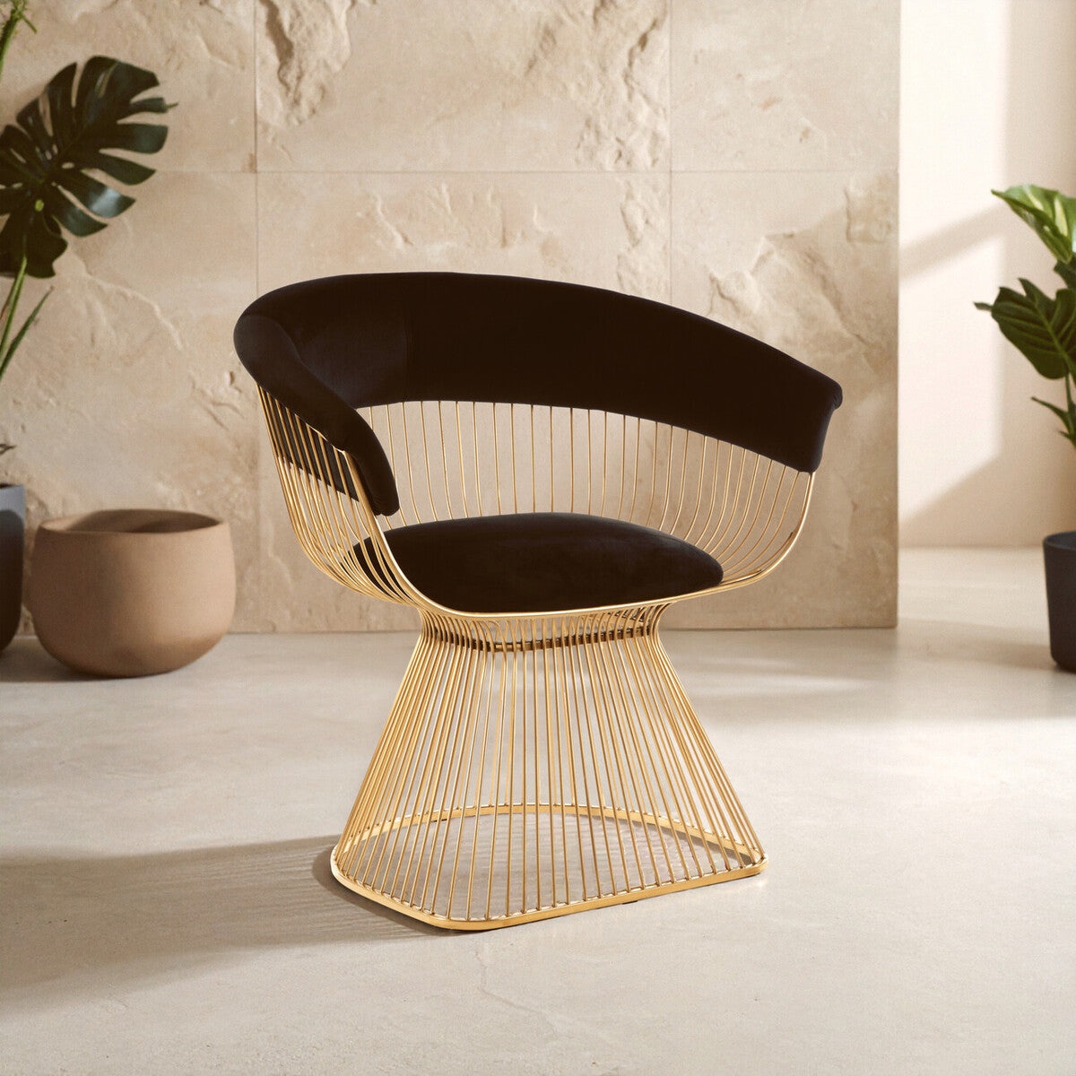 Gold wire chair with black cushion on a light wood floor against a stone wall.