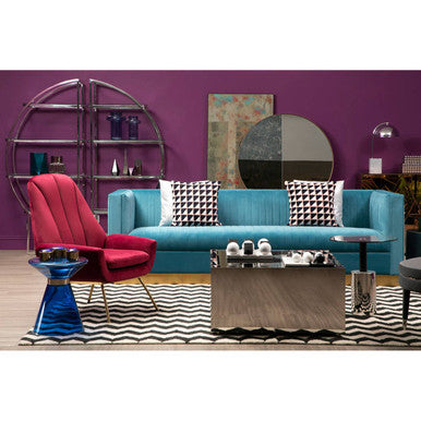 Modern living room with colorful furniture and decor against a purple wall.