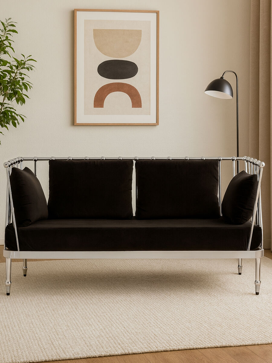 Black sofa with silver frame in a room with abstract art and lamp