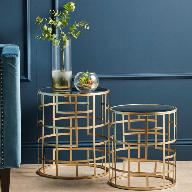 Gold side tables with decorative items against a blue wall
