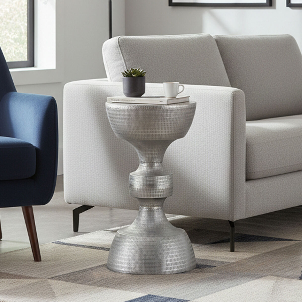 Silver side table in a living room with a gray sofa and blue chair.