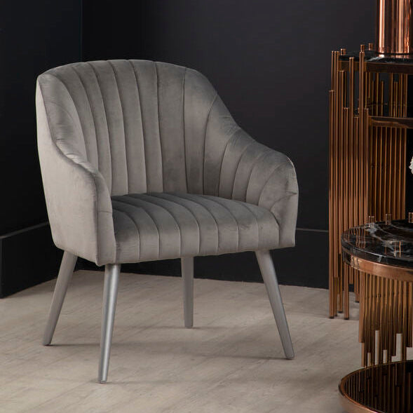 Gray armchair in a modern interior setting with a dark wall and decorative items.