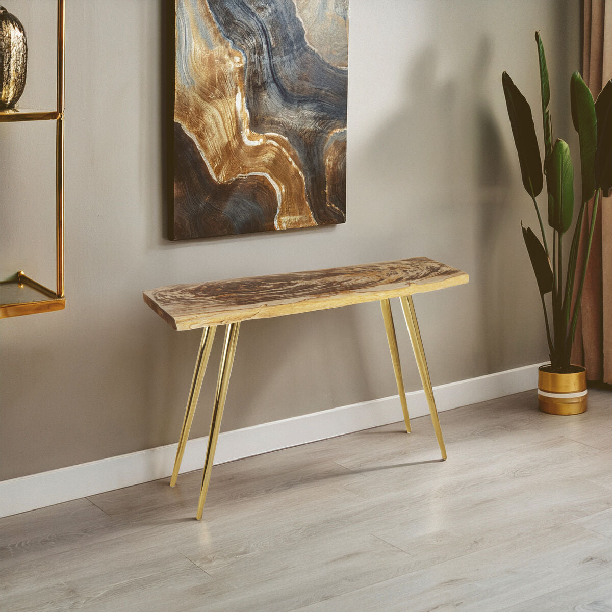 Wooden console table with gold legs in a room with abstract art and plant decor.