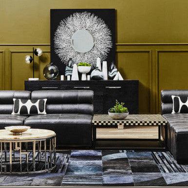 Modern living room with black leather sofa, wooden coffee table, and decorative wall art.