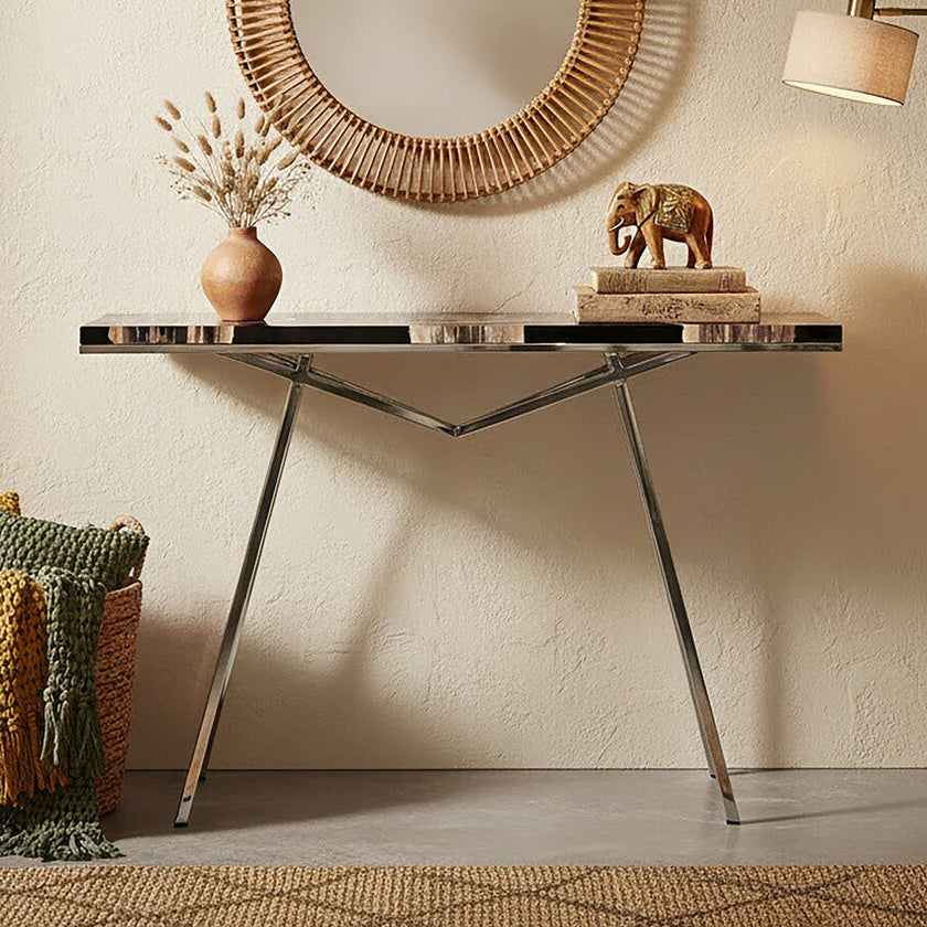 Decorative interior setting with a round wicker mirror, console table, and standing lamp.