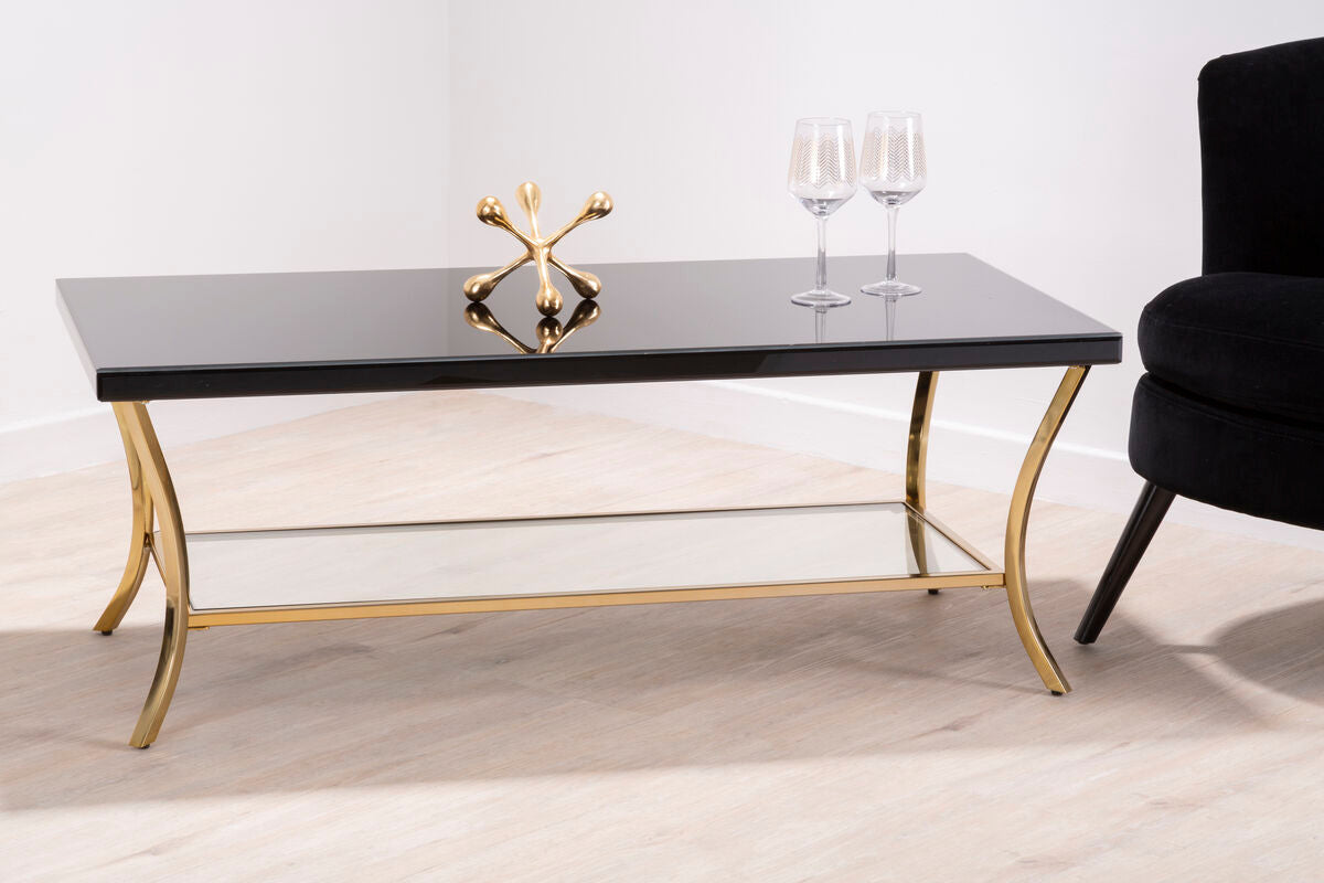 Coffee table with black marble top and gold metal legs in a modern living room setting.