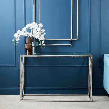 Modern console table with decorative flowers against a blue wall