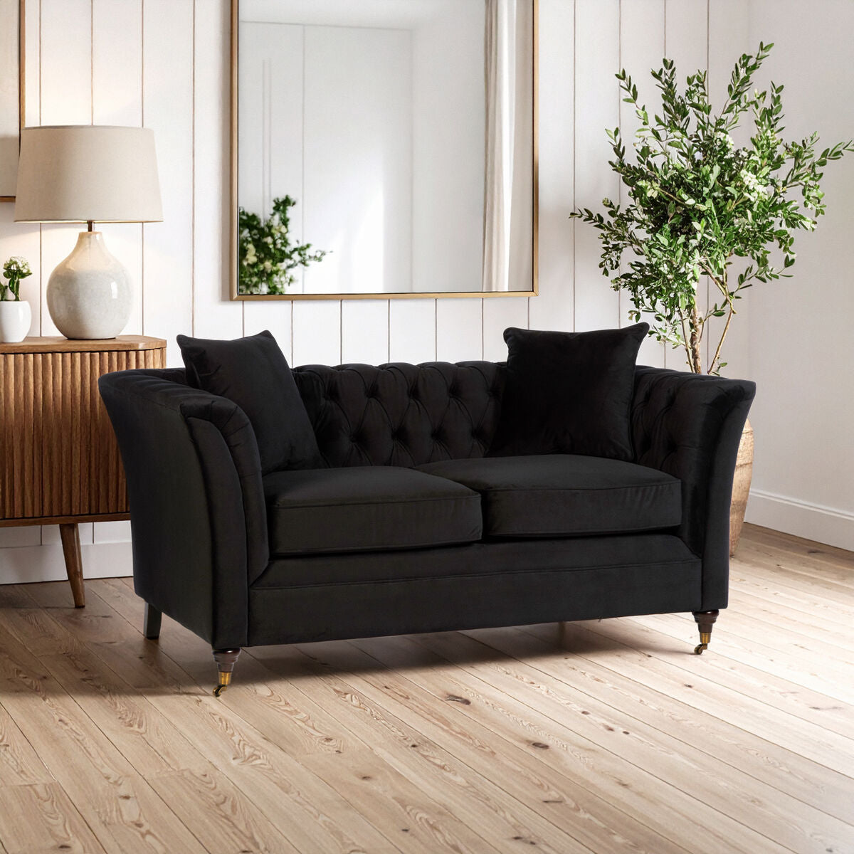 Black sofa in a living room with wooden floor and decorative elements