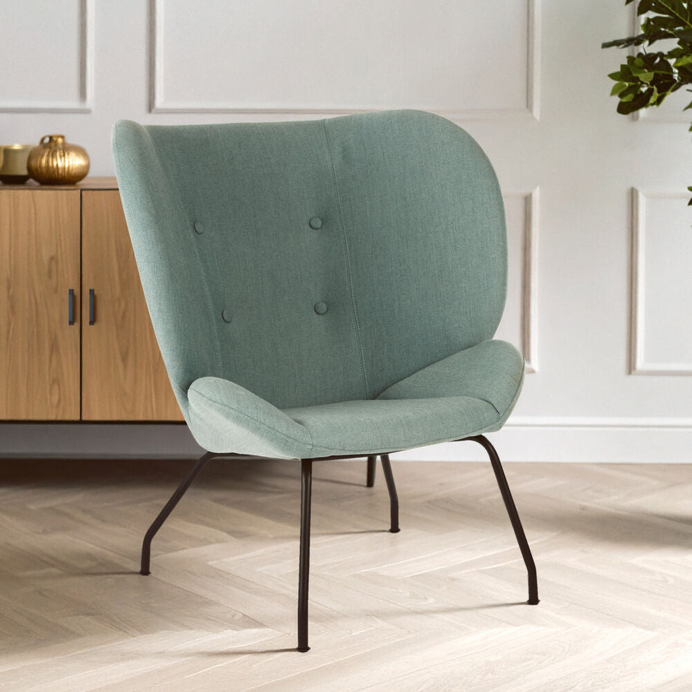 Green chair in a room with wooden floor and white walls