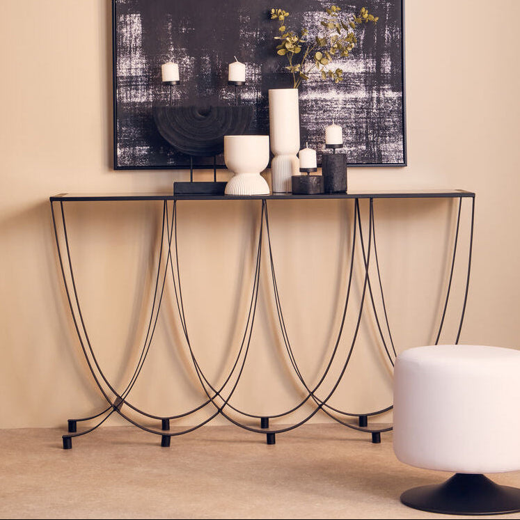 Modern console table with decorative items against a beige wall with abstract art.